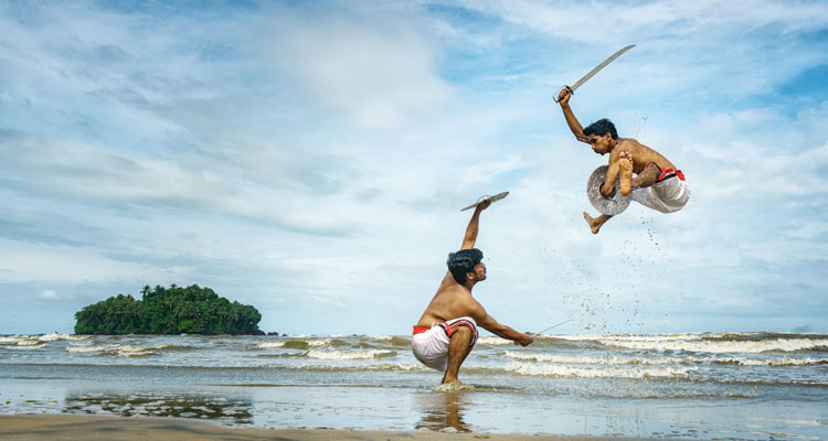 Kalaripayattu -Artists performing Kerala's oldest traditional martial art form on a beach in Kerala, India