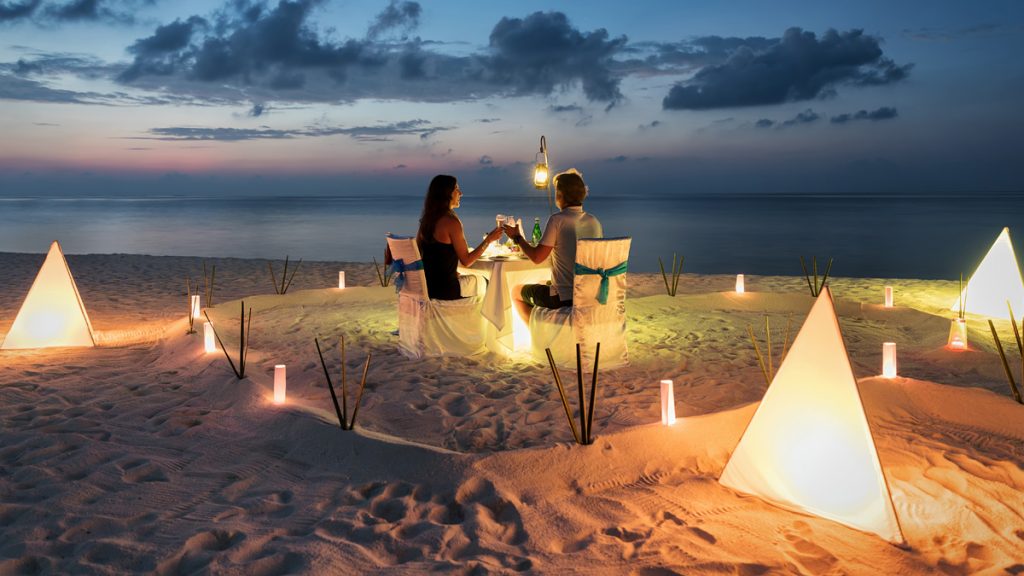 A picture of a honeymoon couple is having a private, romantic dinner at a tropical beach