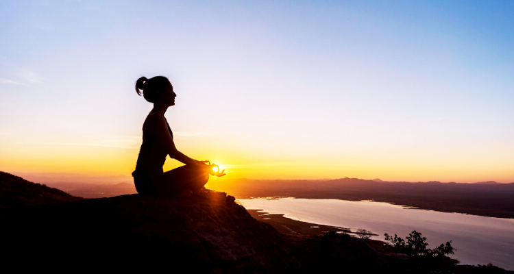 Yoga girl sitting in hill during sunset