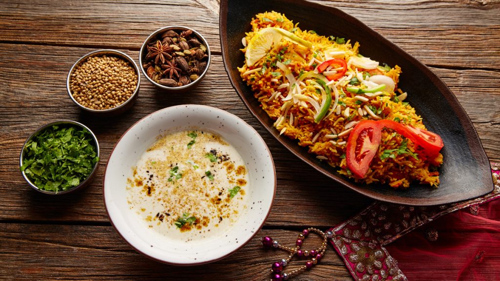 A picture of a Chicken Biryani with white soup and spices.