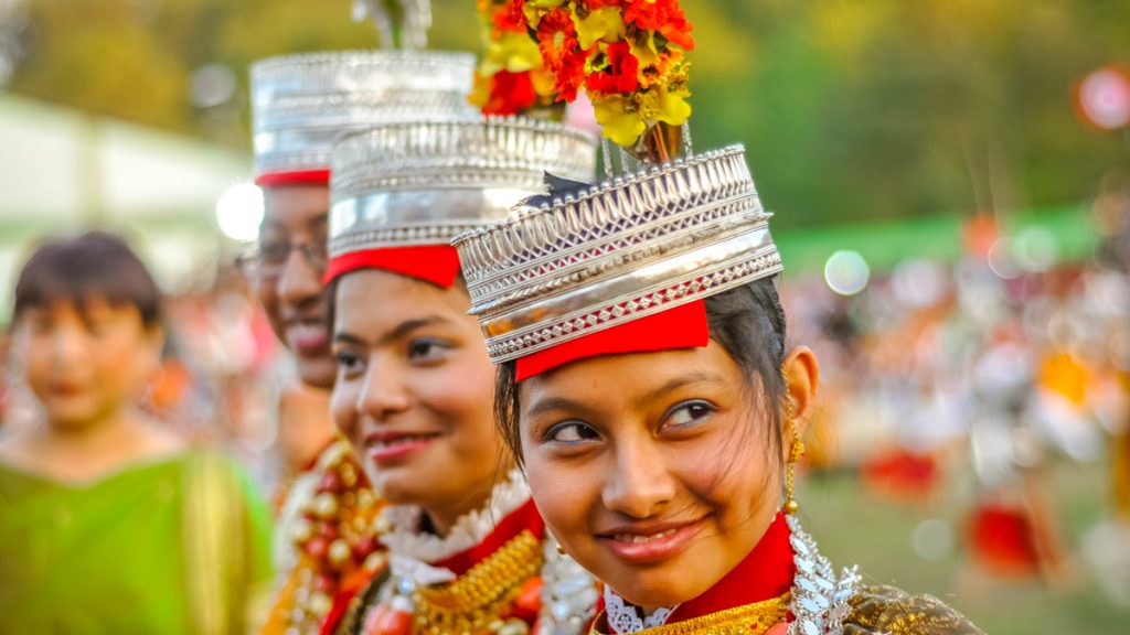 Smiling girls in traditional costumes with large beads and crowns on their heads at Shad Suk Mynsiem Festival in Shillong, Meghalaya.
